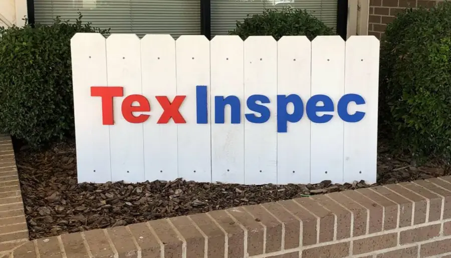 TexInspec storefront sign with red and blue cut letters on a white picket panel